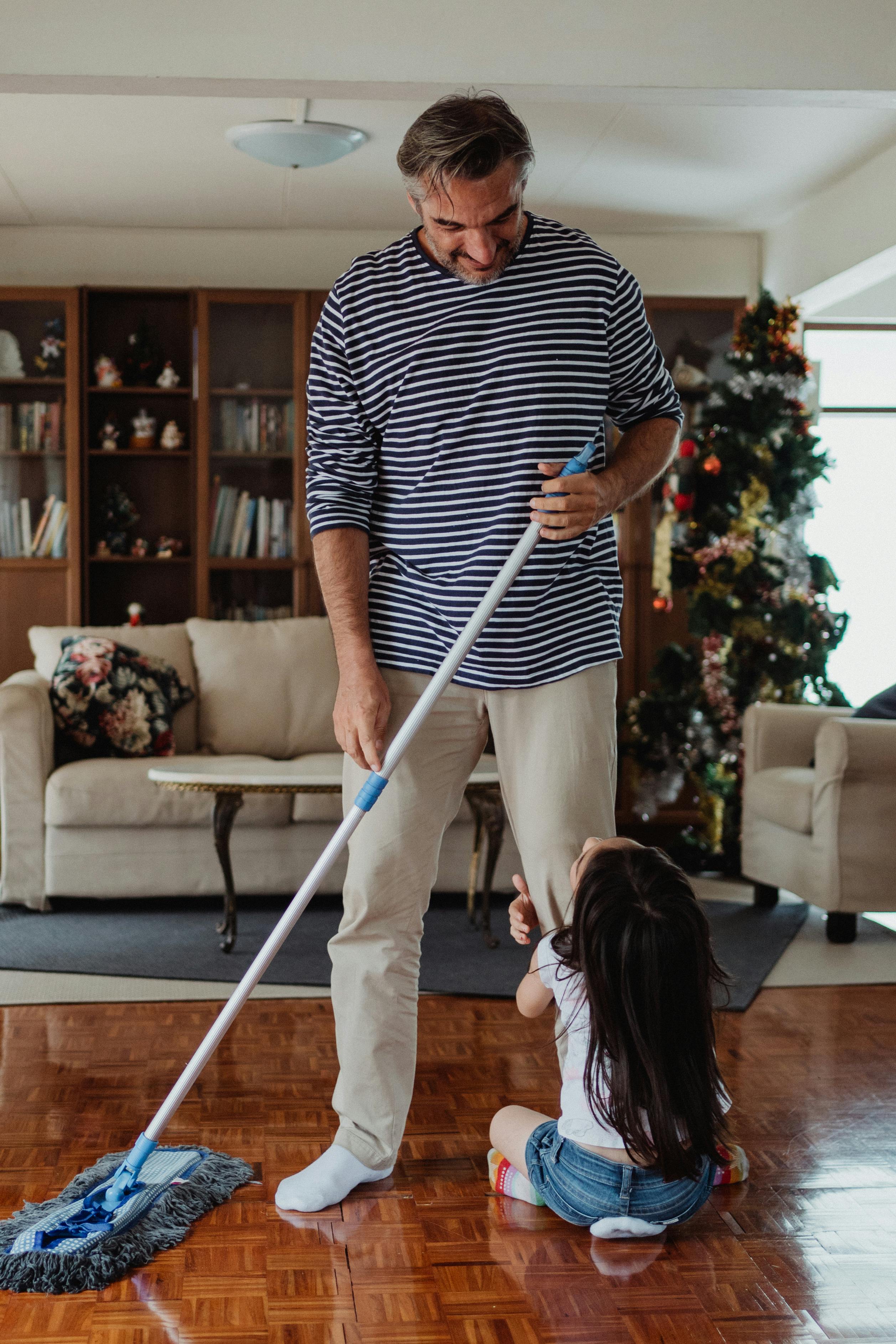 A parent mopping while a child stays close at home.